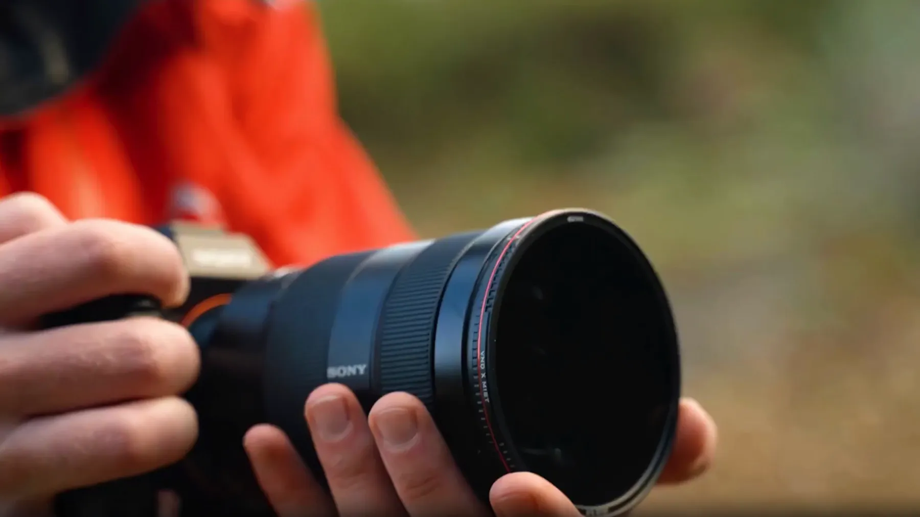 Videographer holding a Sony camera with a telephoto lens